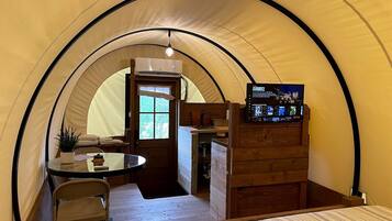 A tent with a kitchenette, a table, and a TV.