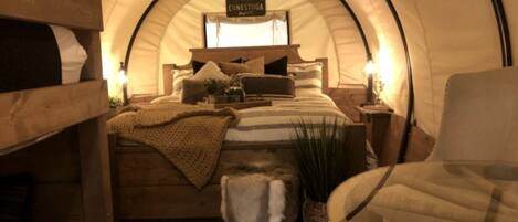 A cozy, arched room with a bed, a chair, and a small bench.