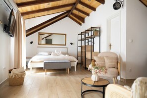 Un dormitorio con cama, un banco, una silla, una mesita, un espejo y un reloj en la pared.