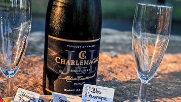 Eine Flasche Charlemagne Wein, zwei leere Gläser und eine Auswahl an Früchten und Nüssen auf einem Tisch.