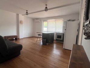 Ein geräumiger Wohnbereich mit einer Couch, einem Esstisch und einer Küche inklusive Kühlschrank und Backofen.
