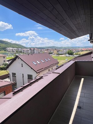 Ein Balkon mit Blick auf Wohnhäuser und eine grüne Landschaft.