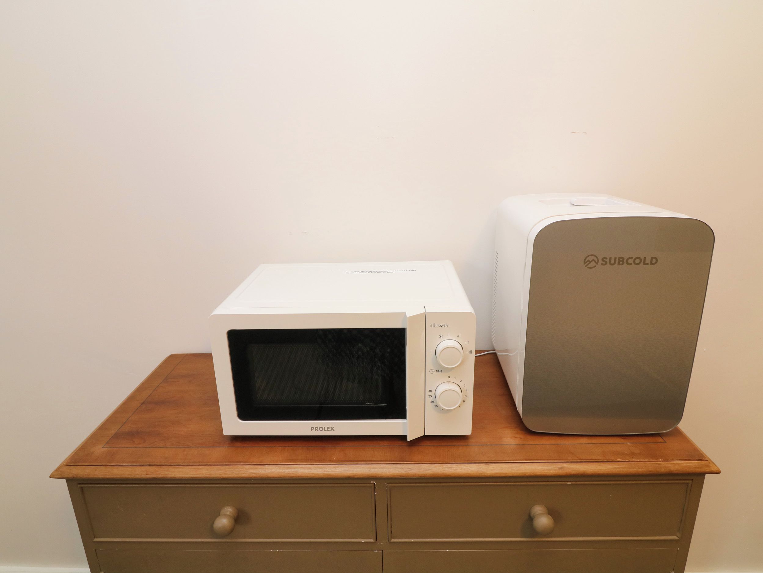 Un four à micro-ondes et un appareil SUBCOLD sont posés sur une table en bois.