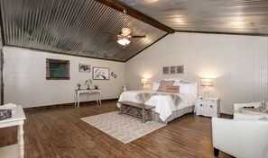 A bedroom with a bed, bedside tables, a ceiling fan, and a wooden floor. - Relaxing Fredericksburg Hill Country Cottages with Porch Swings & Private Wine Collective Access in Texas (Fredericksburg)