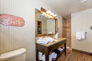 Ein Badezimmer mit Waschtisch, großem Spiegel, Toilette und Duschbereich.