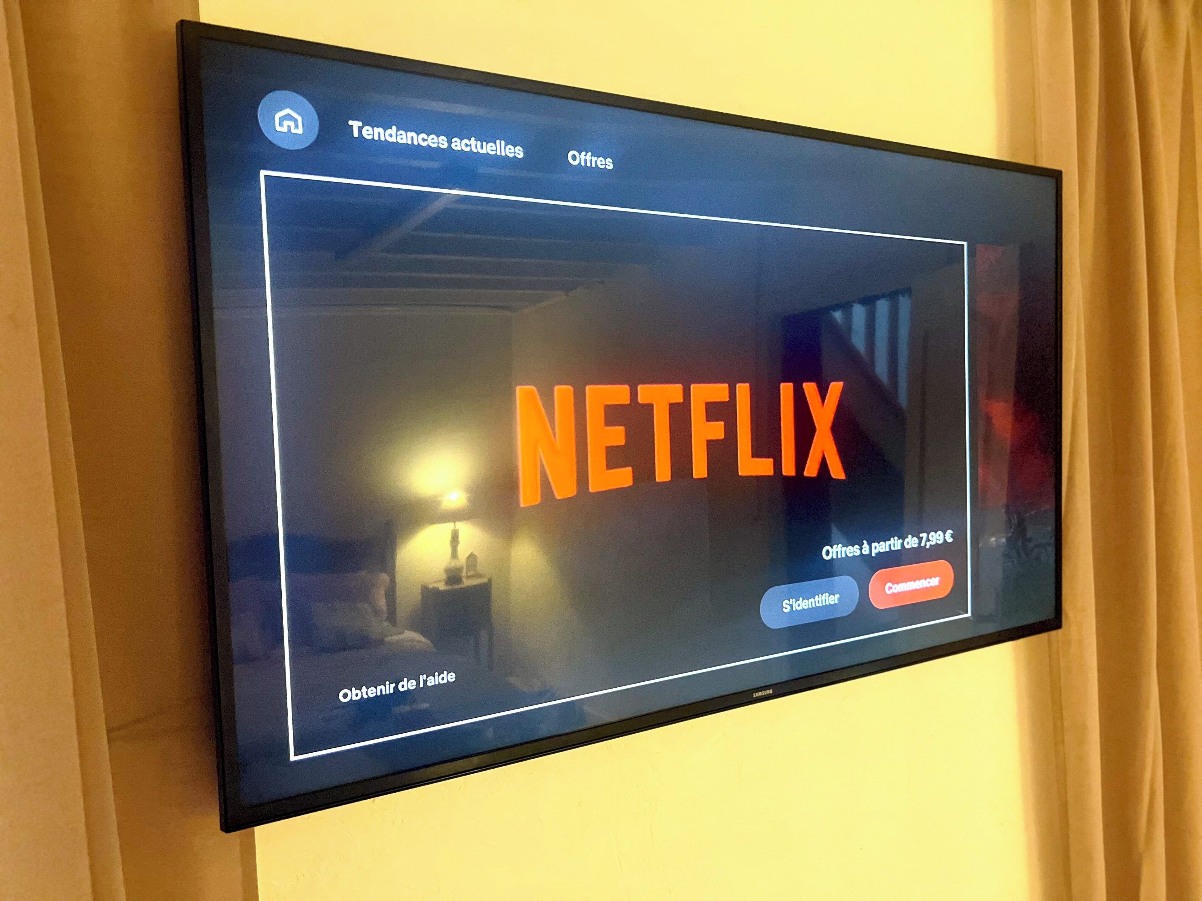 Een televisiescherm toont het Netflix-logo met opties voor actuele trends en aanbiedingen.