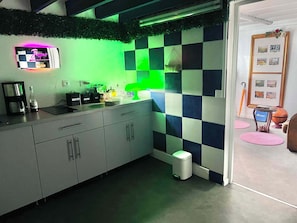 A modern kitchen with a checkered backsplash, a coffee machine, and a trash bin.