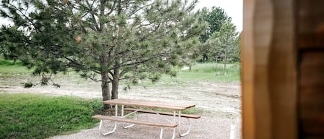 Een picknicktafel met bankjes in een gazon met bomen.