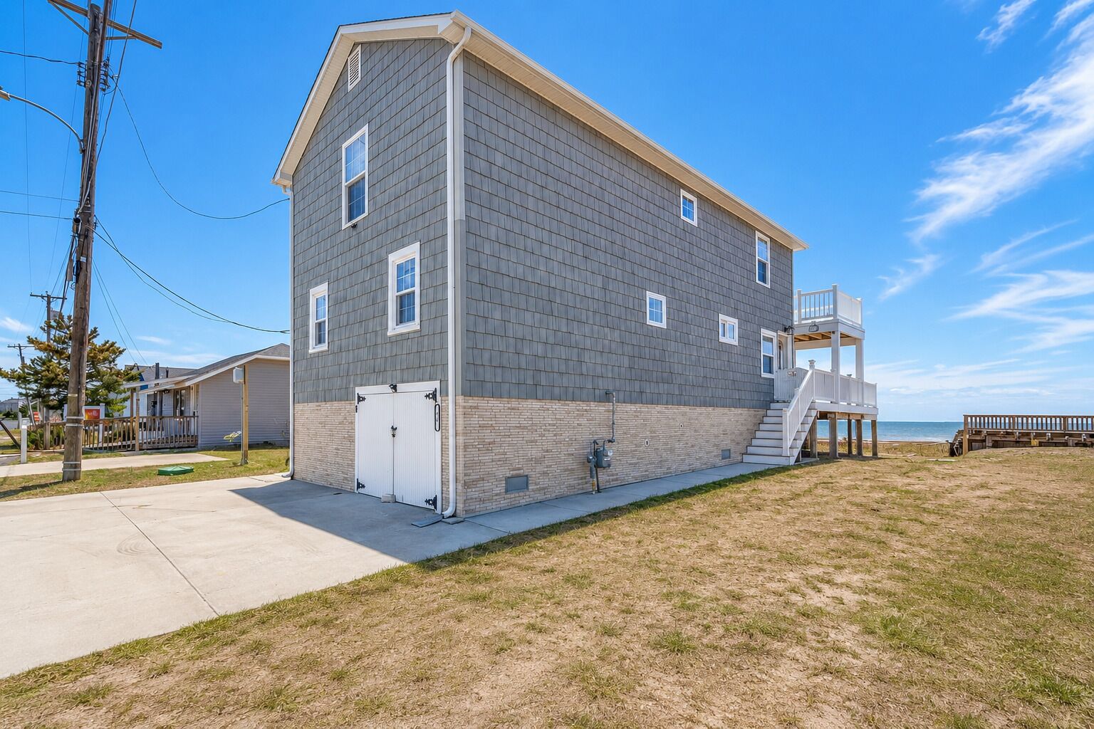 A two-story building with a flat roof, a front porch, and a staircase leading to a second-floor balcony.