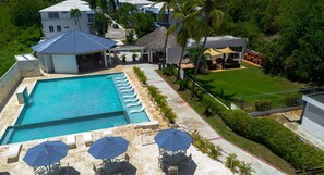Ein Resort mit großem Pool, Terrassenmöbeln und einem gepflegten Rasen.
