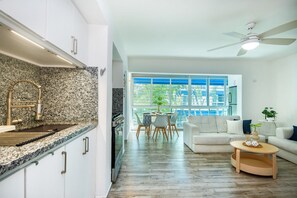 Eine moderne Küche mit Granitarbeitsplatten, einem Backofen und einem Essbereich mit einem weißen Sofa und einem Couchtisch.