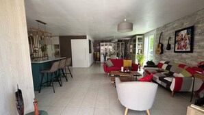 Ampla sala de estar com cozinha, um sofá vermelho, um sofá cinza e uma mesa de centro.
