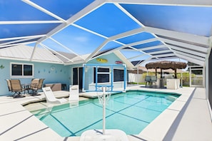 Ein überdachter Pool mit Basketballkorb, Liegestühlen und Essbereich.