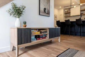 Una sala de estar moderna con una consola de madera, una planta en maceta y una estantería.