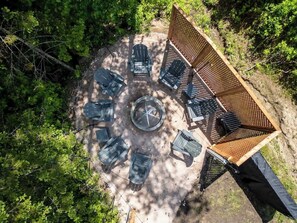Un área de estar al aire libre con sillas dispuestas en círculo y un hogar central.