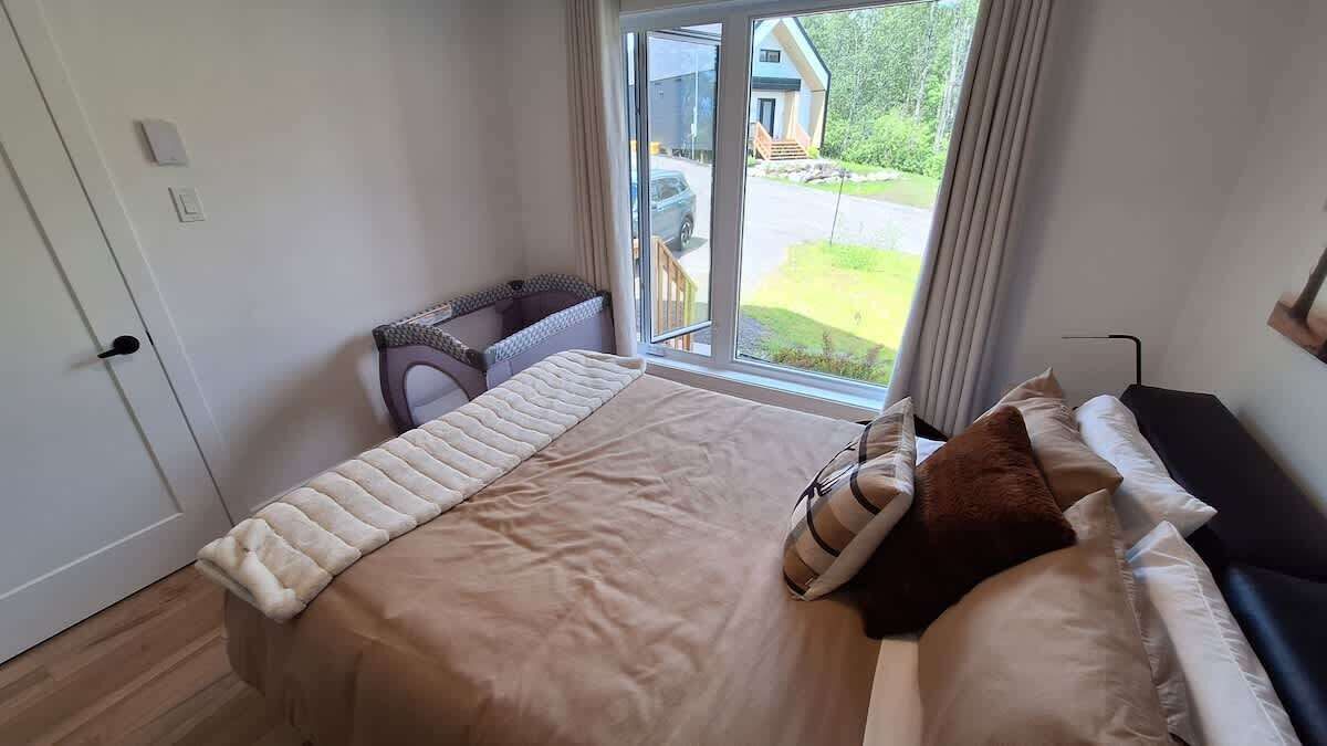 Un dormitorio con una cama grande, un rincón de descanso y vistas al exterior.