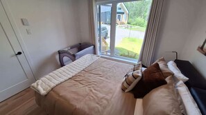 Un dormitorio con una cama grande, un rincón de descanso y vistas al exterior.