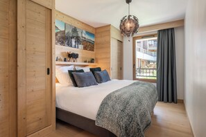 A bedroom with a bed, a painting, a hanging light fixture, and a view of an outdoor balcony. - Lumea - Terrace | Spa | Mtn views | Alpe d'Huez (Huez)