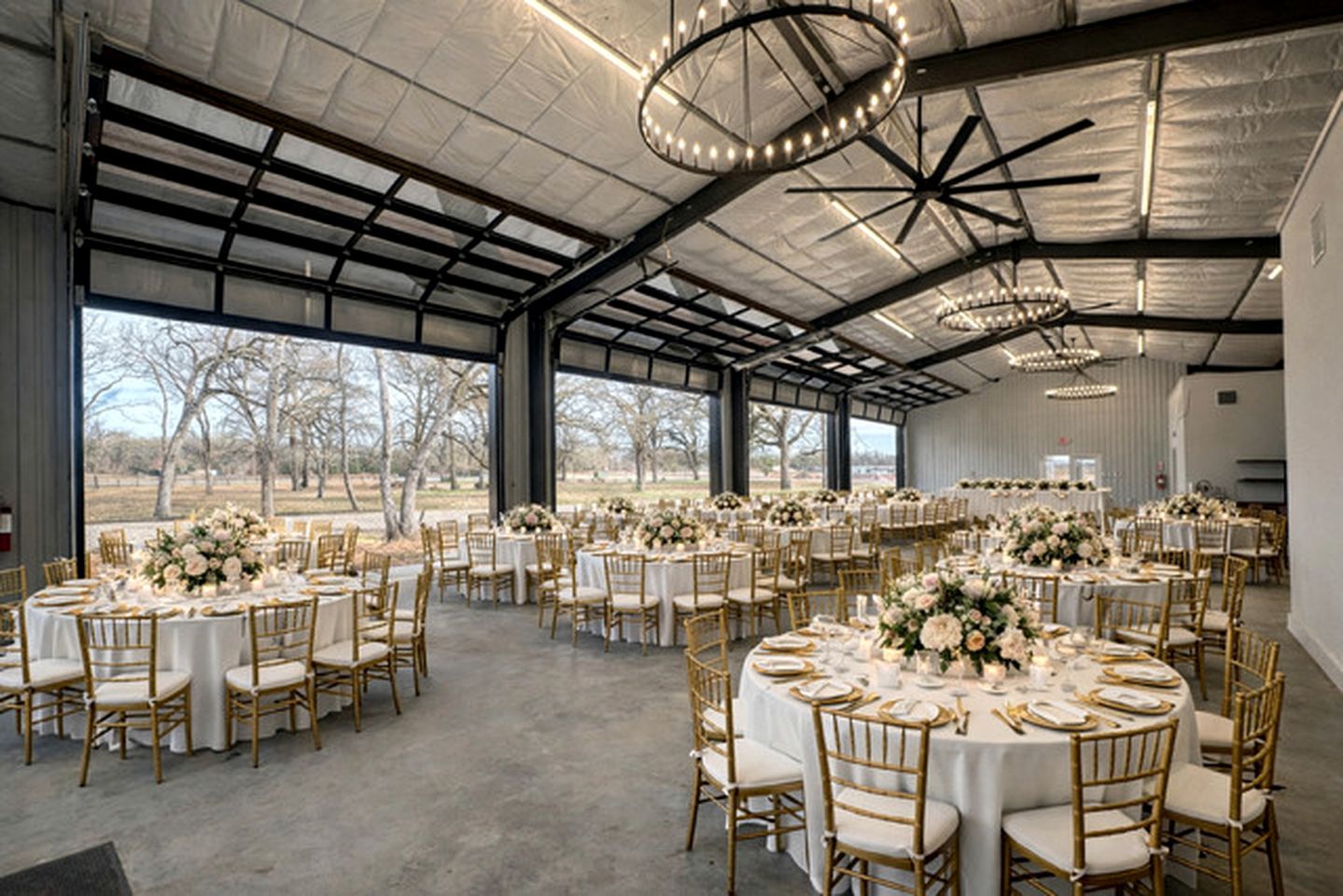A spacious indoor venue with round tables and chairs, large windows, and a high ceiling.