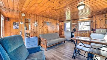 Ein Interieur einer Holzhütte mit einer Couch, einem Esstisch, einer Küchenzeile und Holzwänden.