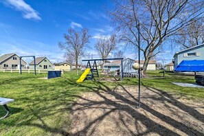 A playground with a yellow slide and swings, surrounded by houses and trees. - Lakefront Cottage with Fire Pit, Beach & Pet Friendly in Houghton Lake, Michigan (Houghton Lake)