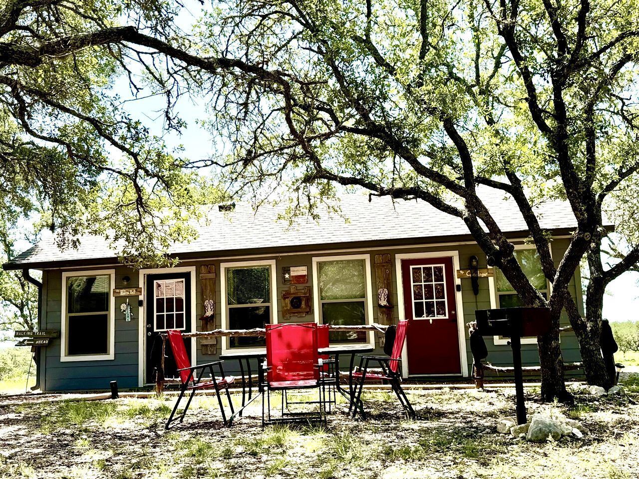 A rustic cabin with a porch, a dining table, and chairs.