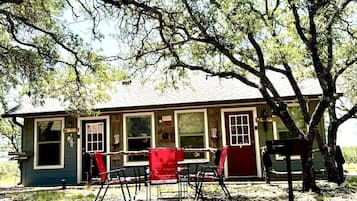 A rustic cabin with a porch, a dining table, and chairs.