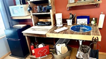 A kitchen with a wooden countertop, a coffee maker, a microwave, and various kitchen utensils.