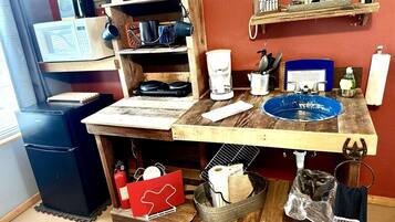 Una cocina con encimera de madera, cafetera, microondas y diferentes utensilios de cocina.
