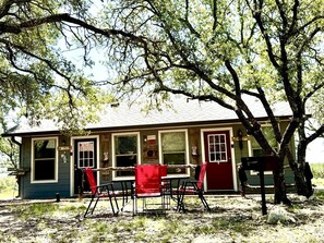 A rustic cabin with a porch, a dining table, and chairs.