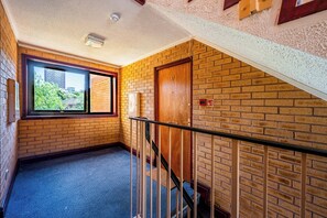 A hallway with a wooden door, a window, and a brick wall. - Stylish Apt·Canals·2 x Free Parking·Sleeps 6 (Birmingham)