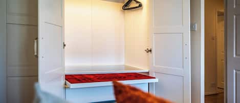 A white closet with a red mat at the bottom, a hanging rod, and a door with a handle.