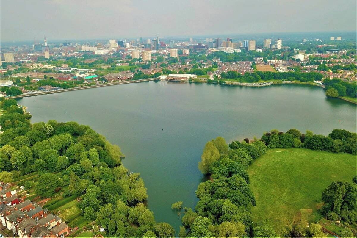 Une vaste étendue d’eau entourée de verdure et de bâtiments urbains.