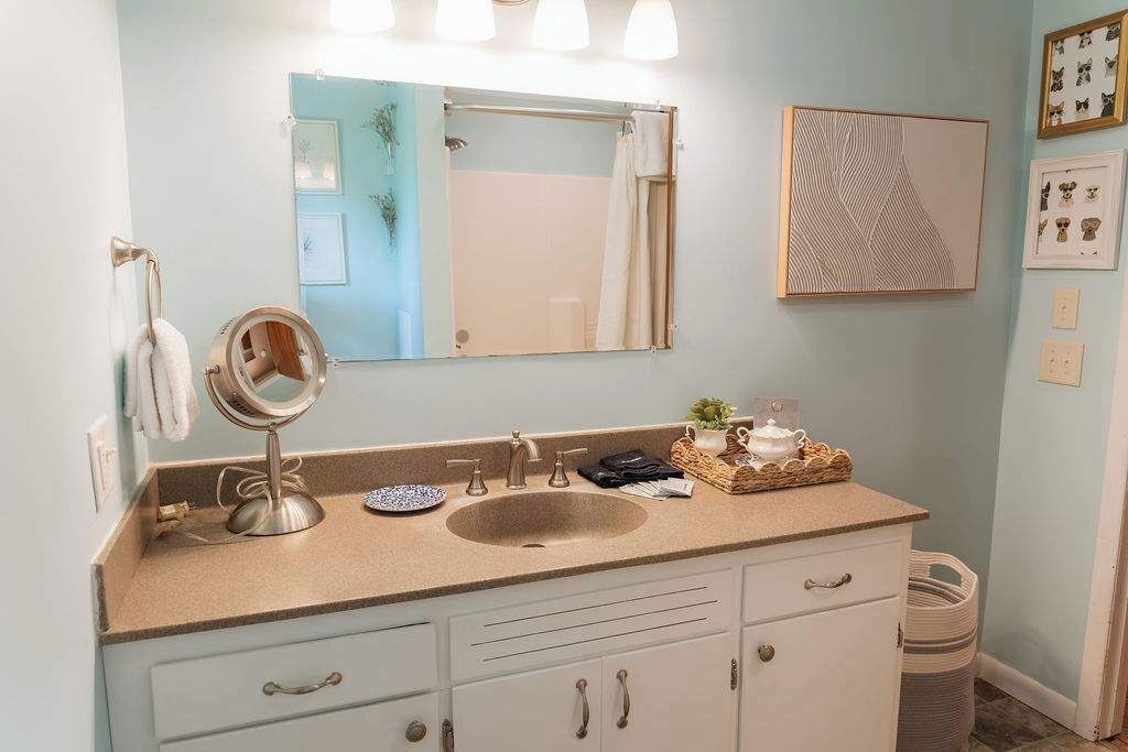 A bathroom with a sink, mirror, and towel rack.