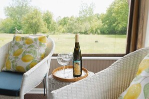 Ein Korbstuhl mit Kissen, eine Weinflasche und ein Glas auf einem gewebten Untersetzer.