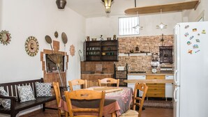 A kitchen with a brick wall, wooden furniture, and a white refrigerator. - Il Casolare Siciliano (Palmeri - Ferrante)