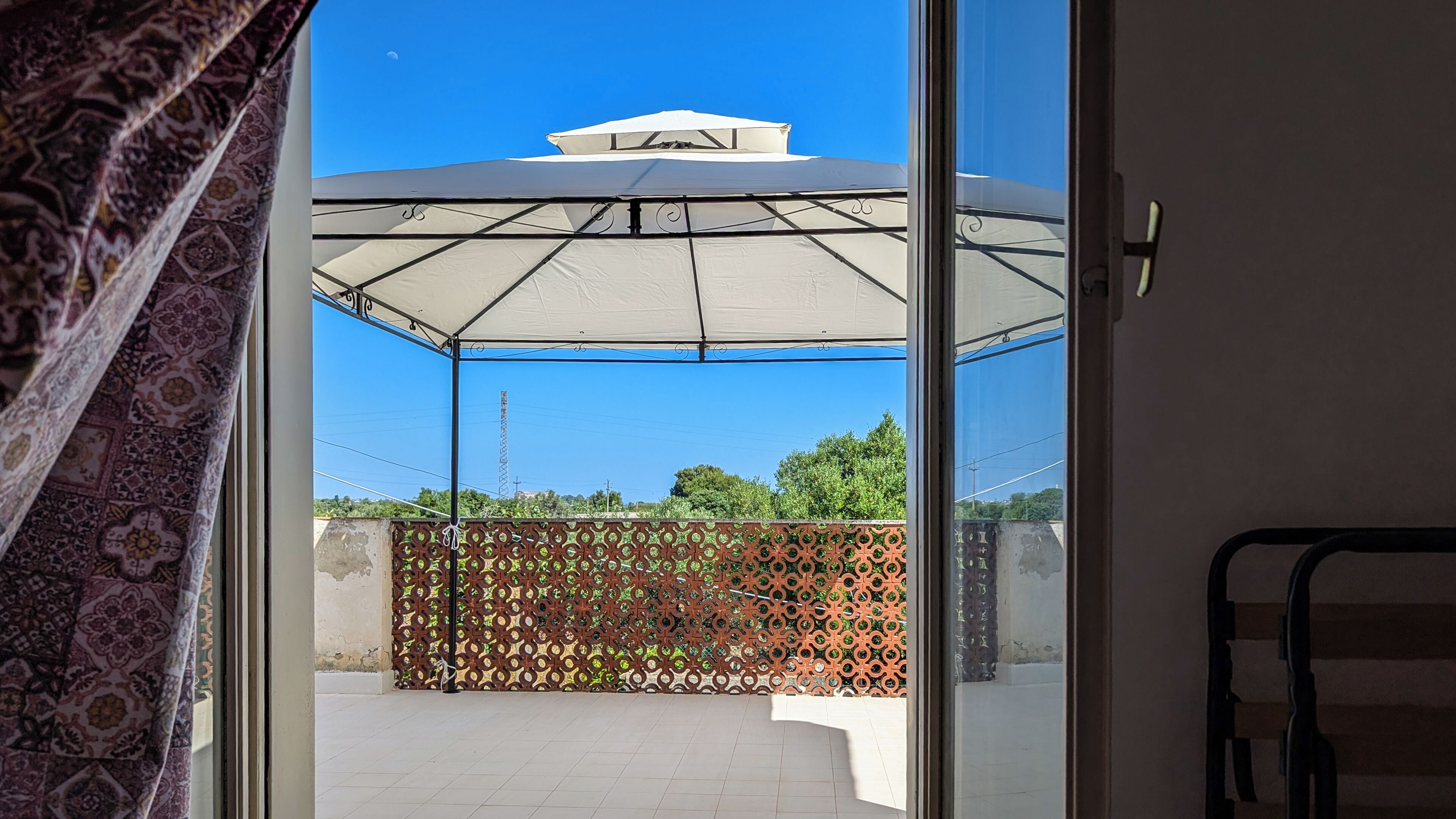 Un espacio al aire libre cubierto con una cerca estampada y un toldo blanco.