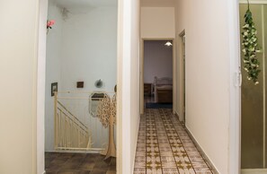 Ein Flur mit einem gemusterten Boden, einem Metallgitter und einer Tür, die zu einem Schlafzimmer führt.