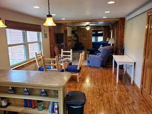 A cozy interior with a wooden dining area, a sofa, and a table.