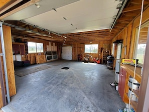 A spacious garage with a concrete floor, wooden walls, and a metal door.