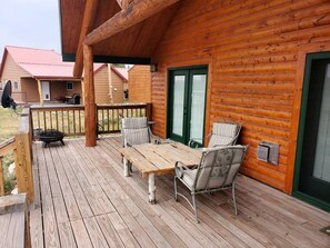 Una cabaña de madera con terraza, una mesa y dos sillas.