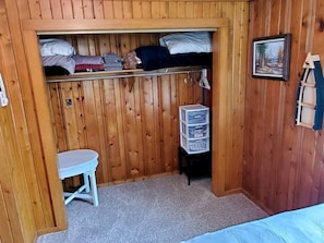 A small room with a bunk bed, a white table, and a storage unit.