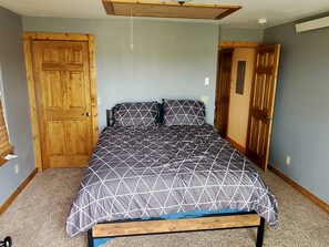 Ein Schlafzimmer mit einem Bett, Holztüren und einem Deckenventilator.