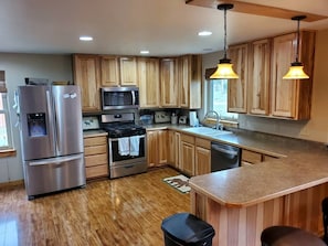 A kitchen with wooden cabinets, stainless steel appliances, a built-in oven, and a large island with a sink.