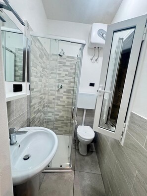A bathroom with a glass-enclosed shower, a white sink, and a toilet. - Apartment 'Ritorno in Liguria' with Wi-Fi and Air Conditioning (Genoa)