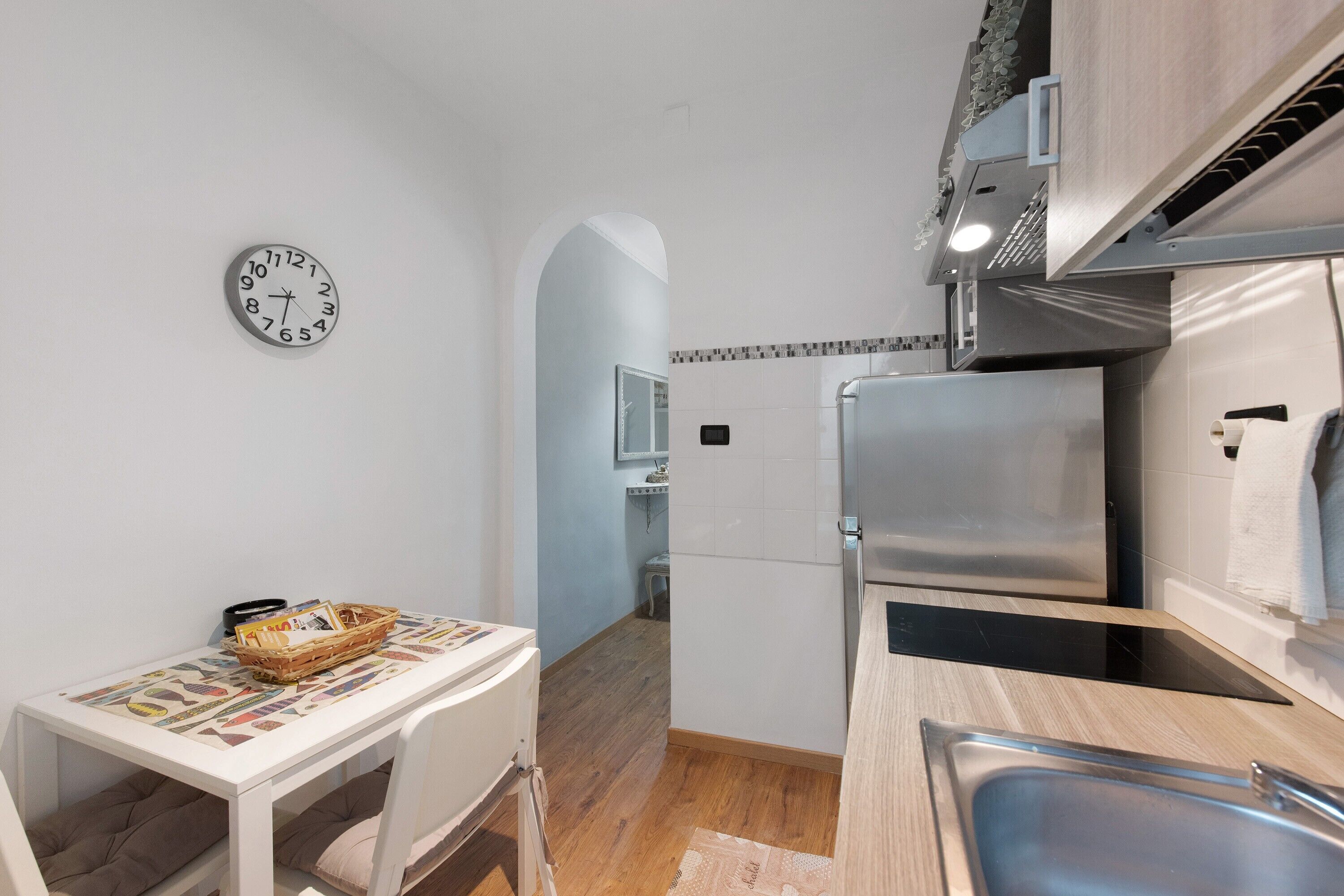Una cucina compatta con frigorifero, lavandino e un piccolo tavolo con un cesto.