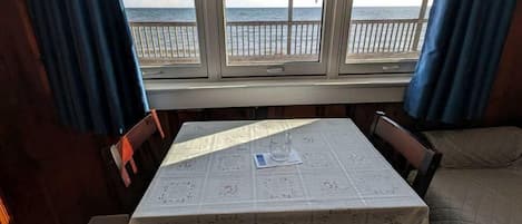 Una stanza con tavolo e sedie, una finestra vista mare e un letto.