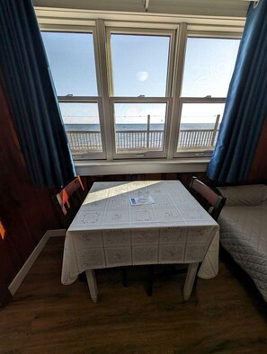 A room with a table and chairs, a window with a view of the sea, and a bed. - Refined Coastal Retreat with Panoramic Sea Views in North Truro, Massachusetts (North Truro)
