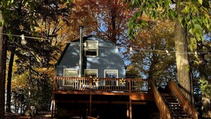 Une cabane dotée d’une terrasse en bois, d’un escalier et d’une fenêtre.