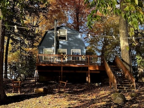 A cabin with a wooden deck, a staircase, and a window.